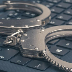 Two handcuffs on a laptop keyboard - Satawa Law, PLLC