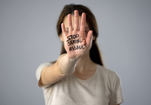 Woman holds up her hand with STOP SEXUAL ASSAULT written on the palm
